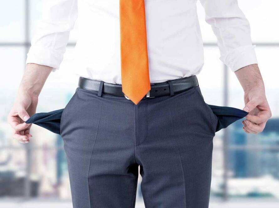 Man in business attire showing empty pockets, symbolizing financial distress or bankruptcy.