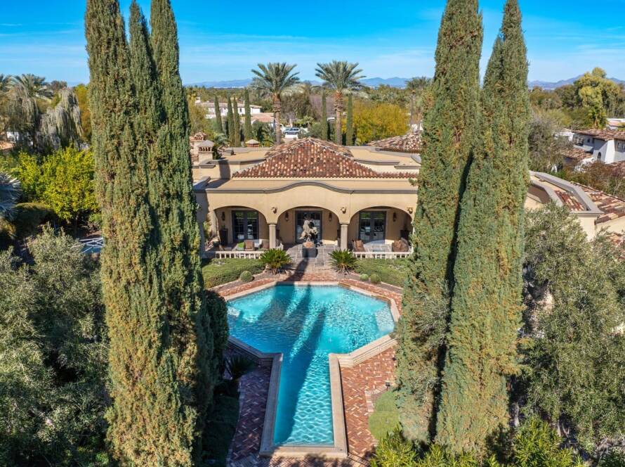 Aerial view of a luxury Scottsdale home with a swimming pool surrounded by trees and desert landscaping.